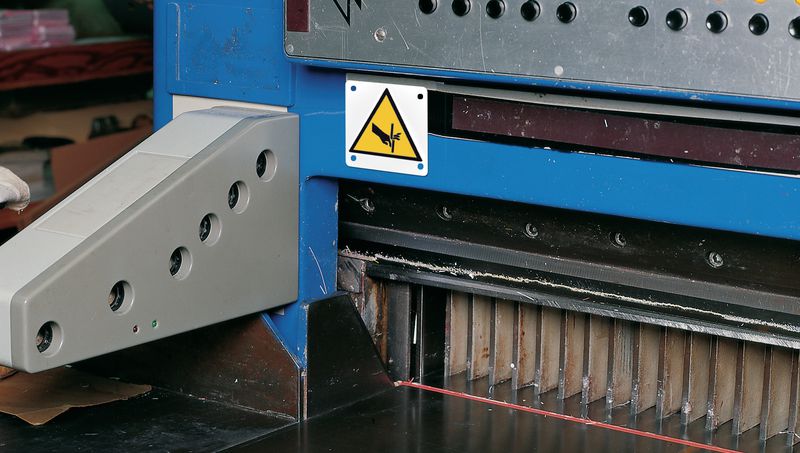Ejemplo Señal advertencia trapamientos: maquinaria industrial con protecciones de seguridad visibles.